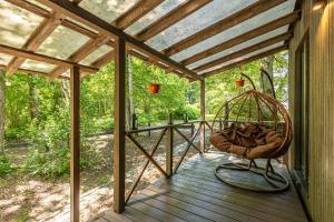 Un porche con una mecedora en una terraza. en Meža māja, en Zaķumuiža