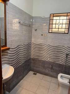 a bathroom with a shower with a sink and a toilet at Marvee Luxus Stay in Coimbatore