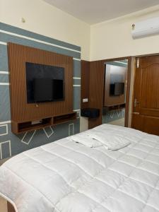a bedroom with a large white bed and a flat screen tv at Marvee Luxus Stay in Coimbatore