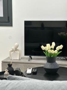 a living room with a tv and a vase of flowers at Helios 1 in Chios