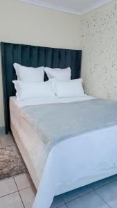 a large bed with white sheets and pillows at Lapeng Mogwase Free Parking-Free WIFI in Mogwase +8 photos