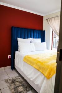 a bed with a blue headboard and a yellow blanket at Lapeng Mogwase Free Parking-Free WIFI in Mogwase