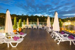 a deck with white lounge chairs and umbrellas at Hotel Zing in Pattaya South