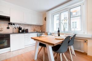 a kitchen with white cabinets and a wooden table and chairs at Alpenheim Apartment in Andermatt