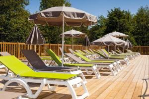 - une rangée de chaises longues et de parasols sur une terrasse dans l'établissement Camping Le Soleil des Landes, à Lit-et-Mixe