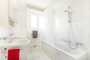 a white bathroom with a sink and a shower at Alpenheim Apartment in Andermatt +5 photos