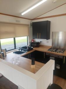 een keuken met een spoelbak en een aanrechtblad bij Amazing Sunsets and Sea Views - Lodge Cabin Farm Stay - Caol Ila - Lodge 8 in Stranraer
