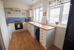 - une cuisine avec un comptoir et un évier ainsi que 2 fenêtres dans l'établissement Sunset Beach House By Air Premier, à Seaford