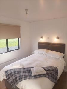 een slaapkamer met een bed met twee handdoeken erop bij Amazing Sunsets and Sea Views - Lodge Cabin Farm Stay - Caol Ila - Lodge 8 in Stranraer
