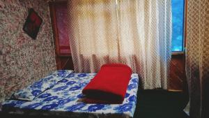 un letto con un cuscino rosso davanti a una finestra di Shanti People Huts And Cafe a Kasol