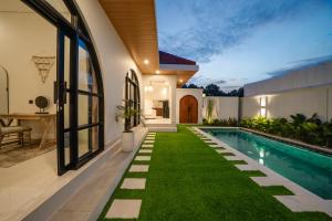 an image of a backyard with a swimming pool and grass at Paica House Nusadua in Nusa Dua
