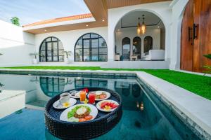 a tray of food on a table next to a swimming pool at Paica House Nusadua in Nusa Dua