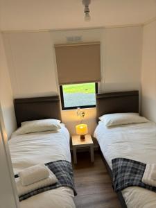 twee bedden in een kleine kamer met een raam bij Amazing Sunsets and Sea Views - Lodge Cabin Farm Stay - Caol Ila - Lodge 8 in Stranraer