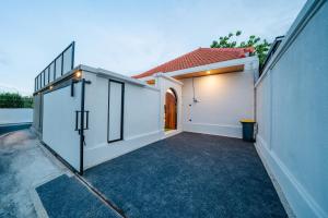 a white house with a gate and a driveway at Paica House Nusadua in Nusa Dua