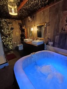 a bathroom with a large blue tub with a sink at La Pensine du célèbre sorcier in Bourogne