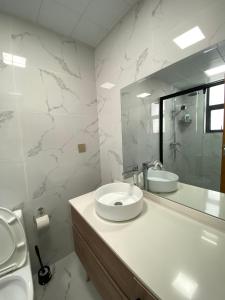 Un baño blanco con lavabo y espejo. en Favorite Staycation by Janice - Modern Comfort Near Airport, en Nairobi