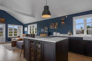 a kitchen with blue walls and an island with a counter top at Modern 4BR Summerhouse with Sauna and Hot Tub in Selfoss