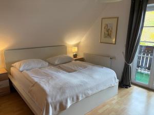 a bedroom with a white bed and a window at Weingut - Ferienhaus Sonja Rohrbacher in Gamlitz