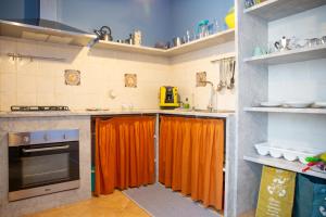 eine Küche mit einem orangefarbenen Vorhang über den Arbeitsflächen in der Unterkunft Solemar Sicilia - Casa Enza in Santa Flavia