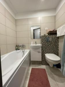 een badkamer met een bad, een toilet en een wastafel bij Central Park studio in Gulbene