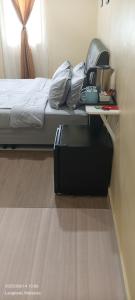 ein Schlafzimmer mit einem Bett und einem Tisch mit einem Koffer in der Unterkunft NURUL ROOMSTAY LANGKAWI in Pantai Cenang