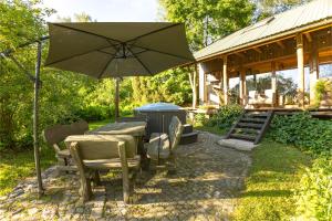 a patio with a table and an umbrella and a grill at Sauleskalns in Zaķumuiža