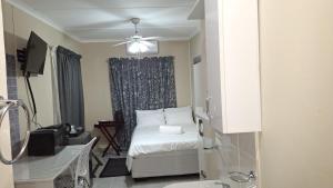 a small bedroom with a bed and a ceiling fan at Serenity in Windhoek