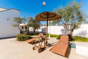 eine Terrasse mit zwei Stühlen und einem Sonnenschirm in der Unterkunft Villa èlitè by Vivimy in Taviano