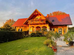a yellow house with a red roof and a yard at Weingut - Ferienhaus Sonja Rohrbacher in Gamlitz +25 photos