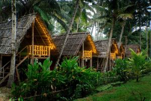 a row of bamboo houses with palm trees at TempleTree Inn in Varkala