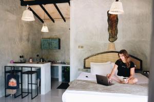 a woman sitting on a bed with a laptop at Birds of Paradise Surf and Yoga Boutique & Retreat in Weligama