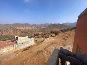 een onverharde weg met een gebouw en bergen op de achtergrond bij house surrounded by trees in a village in Tiznit
