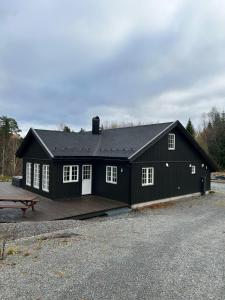 a black building with a picnic table in front of it at Nordre Hella - cabin with Jacuzzi with 4 bedrooms in Fossby
