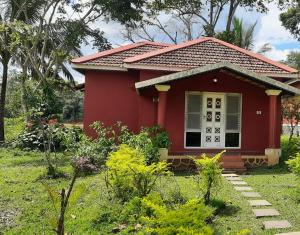 una casita roja en un jardín en Dandeli Chalet, en Dandeli