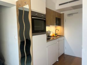 a kitchen with white cabinets and a black microwave at Apartament Niebieski Centrum Sarbinowo in Sarbinowo