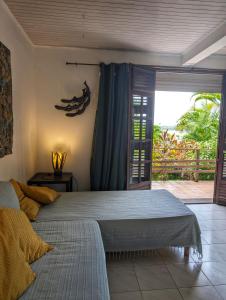 een slaapkamer met een groot bed en een glazen schuifdeur bij Appartement Papay dans Villa Fleurs des Iles in Le Vauclin