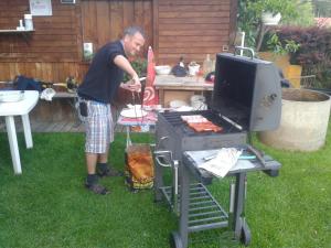 a man is cooking food on a grill at Ferienwohnung Eduard in Mühlen