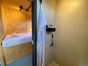 a small bathroom with a shower and a bed at Tiny House The Cabin in Peize