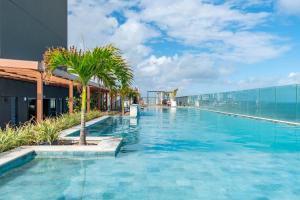 a swimming pool on the roof of a building with palm trees at Apartamento charmoso com Rooftop in Salvador