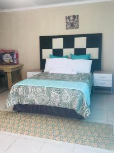 a bedroom with a bed with a black and white headboard at Zalu Lodge in Lusikisiki