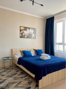 a bedroom with a bed with blue sheets and a window at New апартаменты возле Материнства и Детства in Taldykolʼ