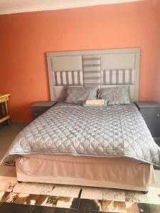 a bedroom with a large bed with an orange wall at Zalu Lodge in Lusikisiki