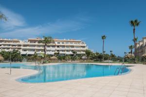 Una piscina con un gran edificio al fondo. en Balcones del Chaparral Peaceful Seafront by Alfresco Stays, en Mijas Costa