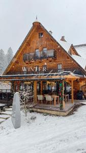 オシュチュニツァにあるHotel Marleneの雪の看板が貼られた大きな木造建築