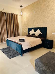 Un dormitorio con una cama grande con cabecero azul. en Bloom Villa, en Mohali