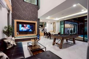 een woonkamer met een pooltafel en een tv bij Ralph Pool Villa Pattaya in Ban Huai Yai