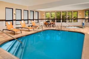 a pool in a hotel with chairs and a table at Courtyard by Marriott Lufkin in Lufkin