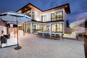 een huis met een zwembad, tafels en een parasol bij Ralph Pool Villa Pattaya in Ban Huai Yai