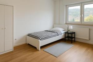 a white bedroom with a bed and a window at Monteur- und Ferienwohnung Bensheim in Bensheim