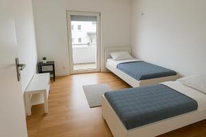 two beds in a white room with a window at Monteur- und Ferienwohnung Bensheim in Bensheim